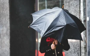 A woman has difficulty holding an umbrella from strong winds in rainy weather.