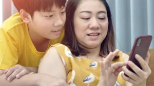 A photo of a mother and son playing on a mobile phone.