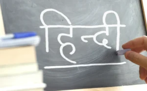Hand writing on a blackboard in a Hindi class. Some books and school materials. Indian language
