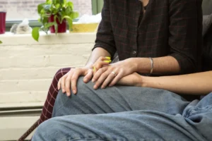 A couple holding hands on a couch.