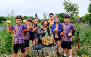 Rangimarie Parata Takurua and pononga (students) harvesting food in the māra kai (garden for food) at Te Pā o Rākaihautū. Left to right: Kade Te Whata-Kururangi, Deegan McGarr, Hineterā Davis, Rangimarie, Wahawaha Winiata, Celia Williams and Hawaiki Jones-Fiso.