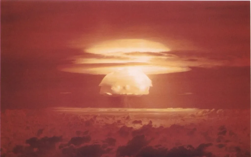 A large, fiery explosion creates a mushroom cloud against a dark red sky.