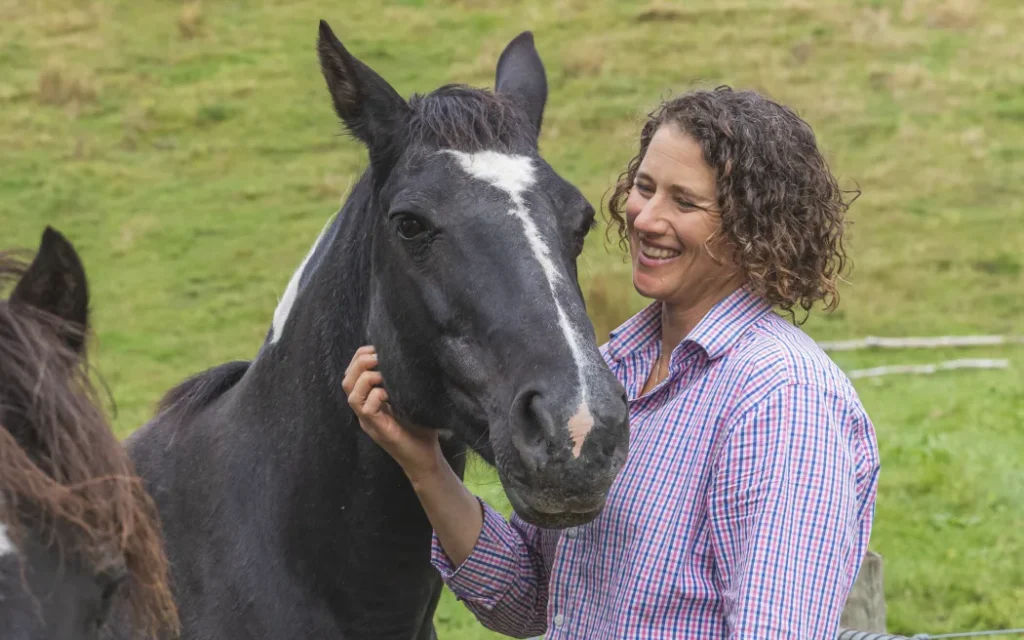 Storm Baynes-Ryan smiling and stroking a black horse