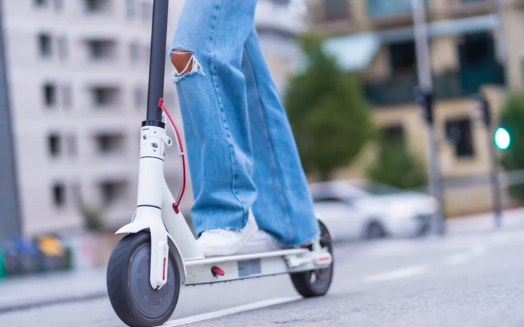 Detail of a young brunette woman moving in the city with an electric scooter