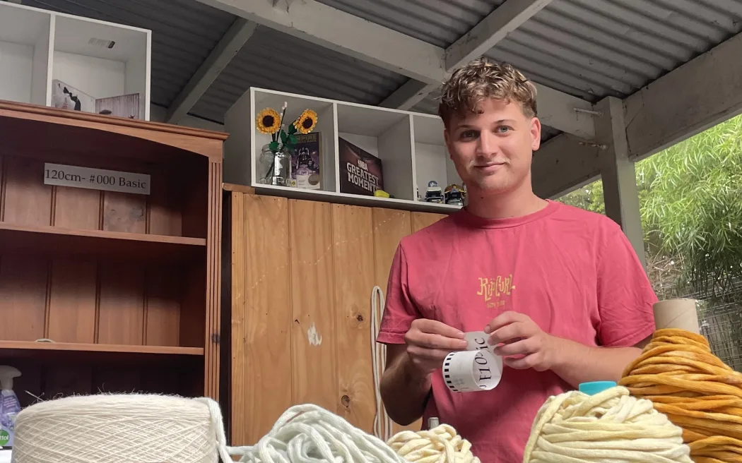 Jacob Smith in his studio with rolls of shoelace material in front of him