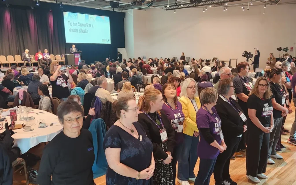Y tá đồng loạt quay lưng, phản đối Bộ trưởng Y tế ngay trong bài phát biểu 1 Nurses Organisation delegates turn their back on Health Minister Simeon Brown during his speech to the NZNO conference in Wellington, 17 September 2025.