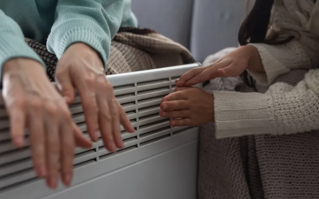 Sốc: Hàng trăm nghìn hộ gia đình bị phạt phí trả chậm tiền điện, Consumer NZ lên tiếng 1 Family warming hands near electric heater at home, closeup.