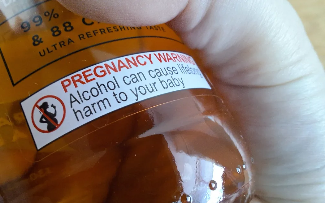 Stock image of alcohol in pregnancy warning label on bottle of beer