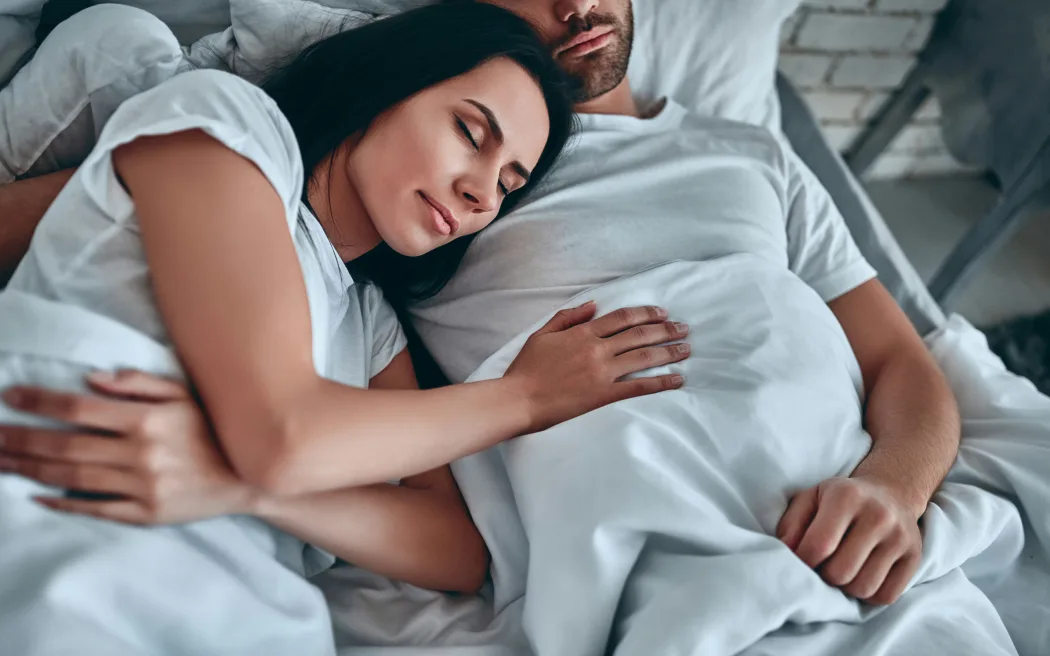 A couple sleeping together in bed.