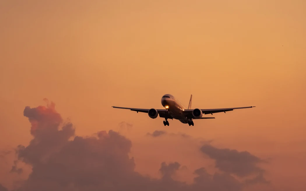 Commercial airline. Passenger plane landing at airport with beautiful sunset sky and clouds. Arrival flight. Airplane flying in a line for landing. Aircraft open light in the evening flight.