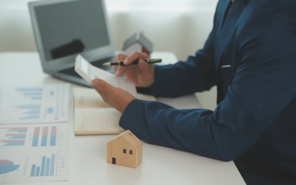 Businessmen holding pens, signing home titles with insurance.
