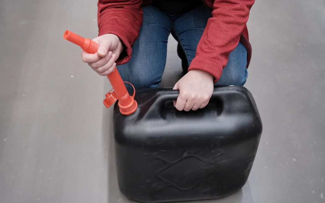 Woman in the parking lot store chooses for buys a canister with a flexible hose under fuel.