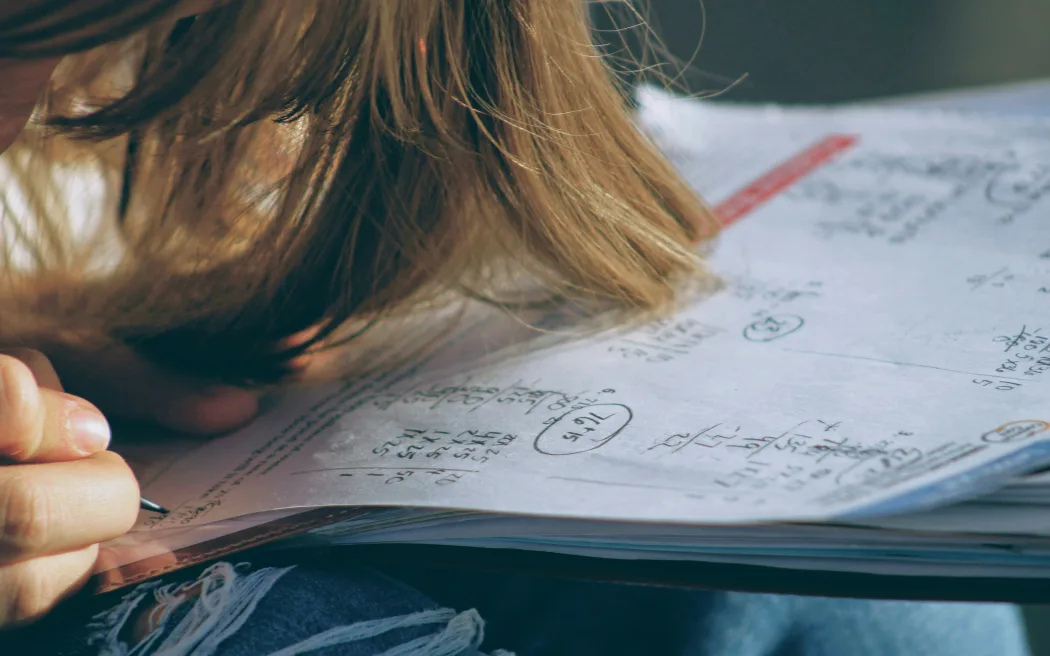 A teenager working on maths problems on a worksheet.