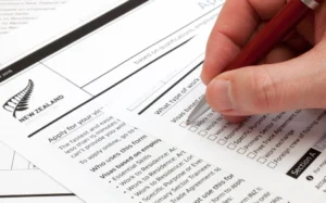 A man holding a ballpoint pen to fill a work visa application form to New Zealand.