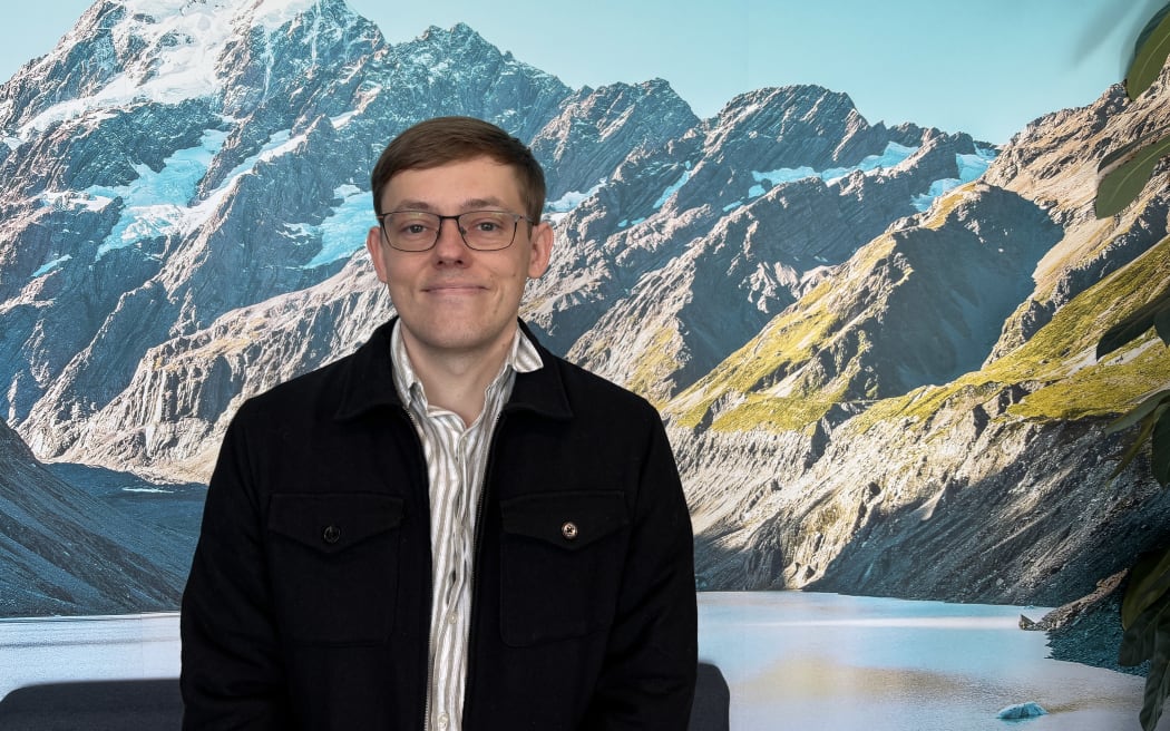 Dr Andrew Lensen, senior lecturer in AI and programme director of AI at Victoria University of Wellington against a background of snowcapped mountains.