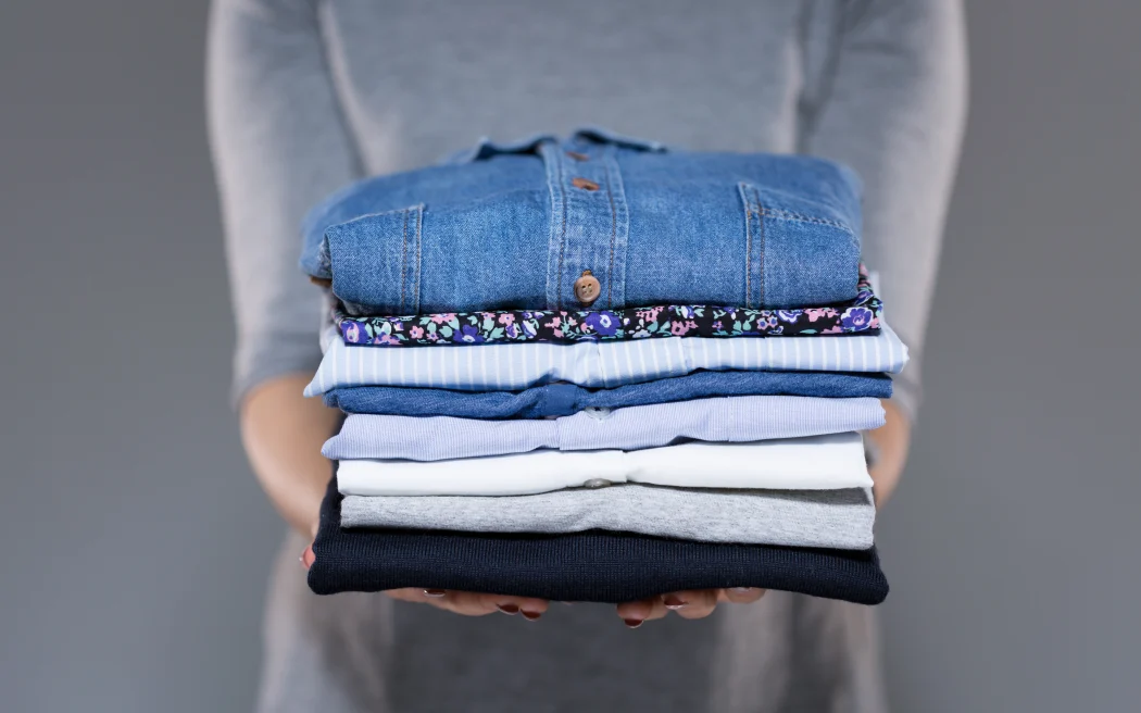 Woman holding folded clothes in hands