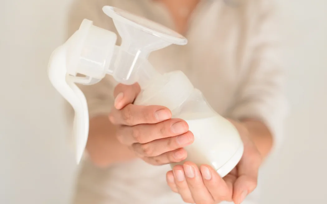 Mother holds breast pump in her hand, blurred background
