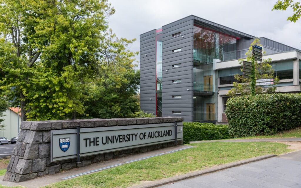 Đại học Auckland 'quay xe' bất ngờ: Hủy bỏ môn học bắt buộc về Hiệp ước Waitangi sau làn sóng phản đối dữ dội 1 Auckland, New Zealand - March 1, 2017: Sign and logo of University of Auckland set near modern dark gray offices in green park like environment.