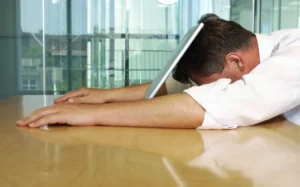 Businessman lying with face on laptop. (Photo by Téo Lannié / AltoPress / PhotoAlto via AFP)