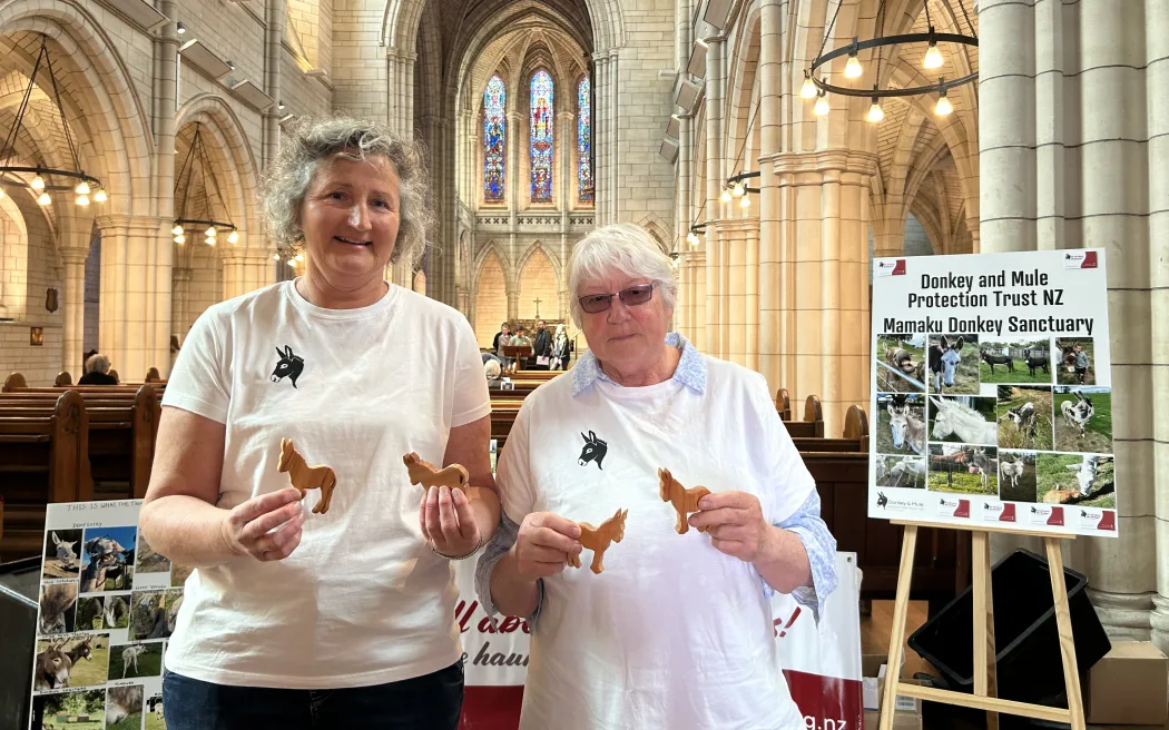 Portrait of two woman holding donkey shaped wood cuttings.