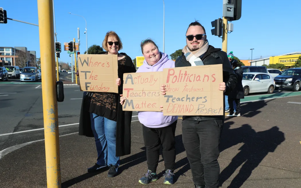 A family of secondary school teachers stand at the intersection of Universal Drive and Lincoln Road in Henderson. They are striking after the government offered them a 1% payrise.