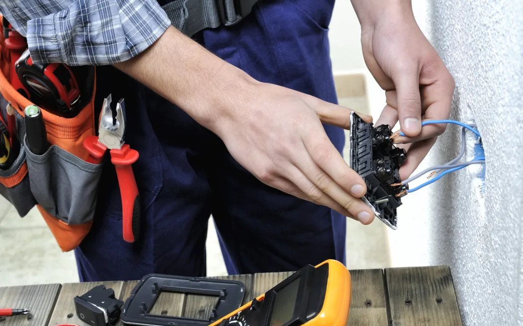Young electrician at work on switches and sockets of a residential electrical installation.