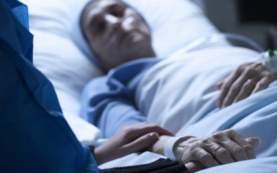 Young woman in hospice care, holding hands in hospital.