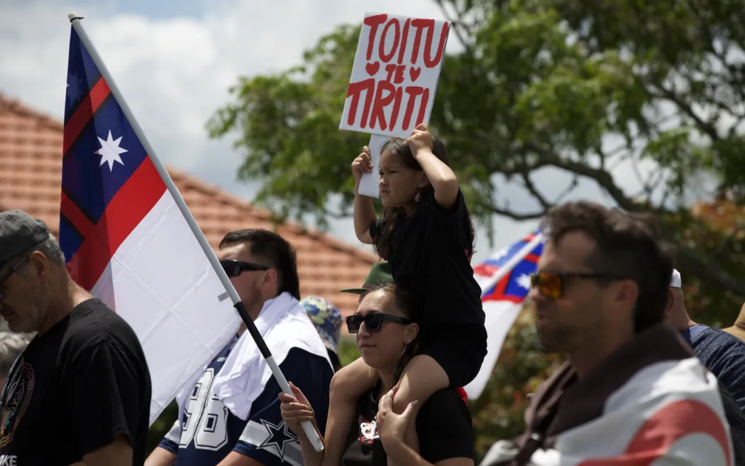 Kōtirotiro holds sign that says 'Toitu Te Tiriti' while marching in Dargaville.