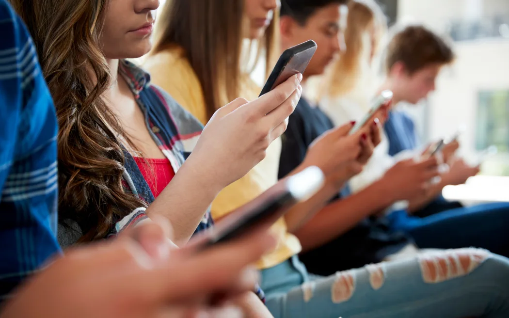 Close Up Of A Line Of High School Students Using Mobile Phones