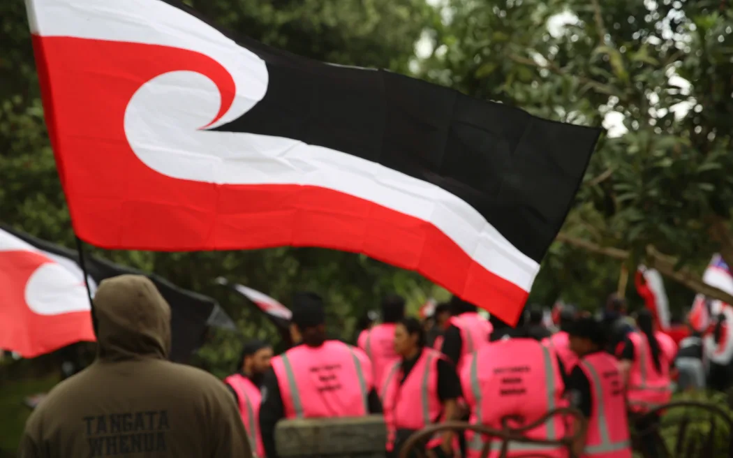 Tāne flys his Tino Rangatiratanga Flag at the Hīkoi mō Te Tiriti in Tāmaki Makaurau.