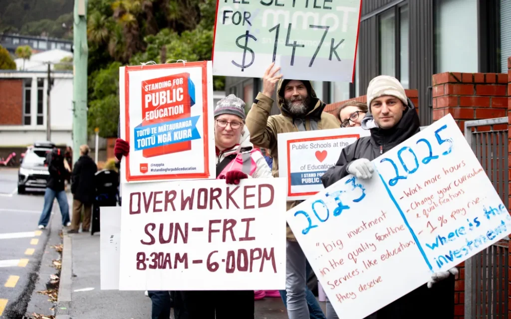 A Wellington protester's sign makes reference to Public Service Minister Judith Collins' error when she said that on average a teacher with 10 years' experience was on an annual salary of $140,000. Collins later said she mixed up her messages and had apologised for the error.