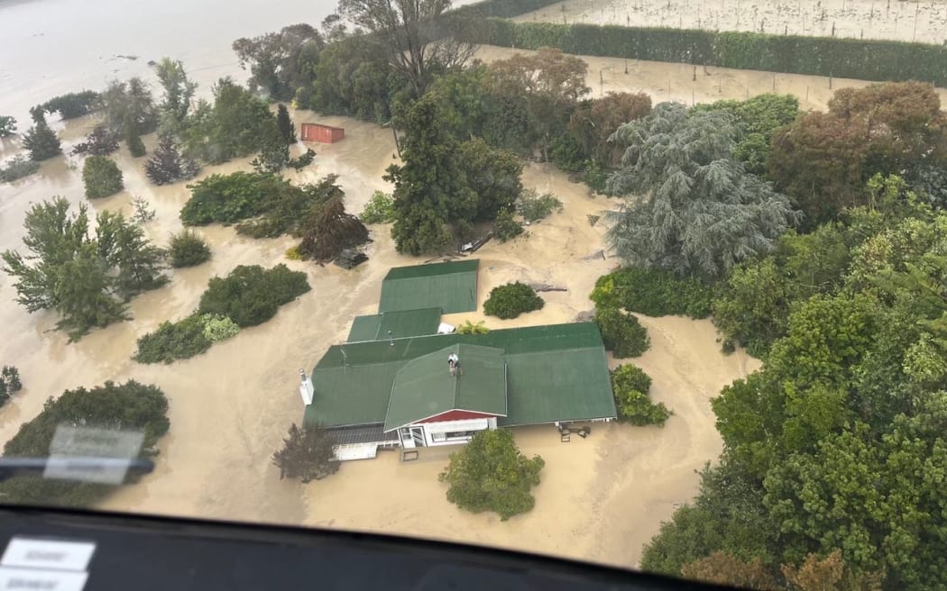 An NH90 helicopter and crew recover people from the rooftops of their homes in Esk Valley, Napier.