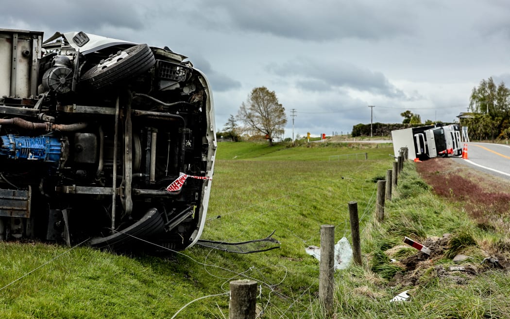 Two refrigerated trucks lay on their sides after toppling on an exposed part of SH1 just outside of Balclutha